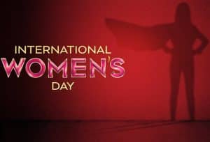 Image of a female superhero on a red background with the words International Women's Day in glittering letters