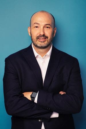 Image of Mike Voight, Merit Medical Chief Human Resources Officer, folding his arms, leaning against a blue wall