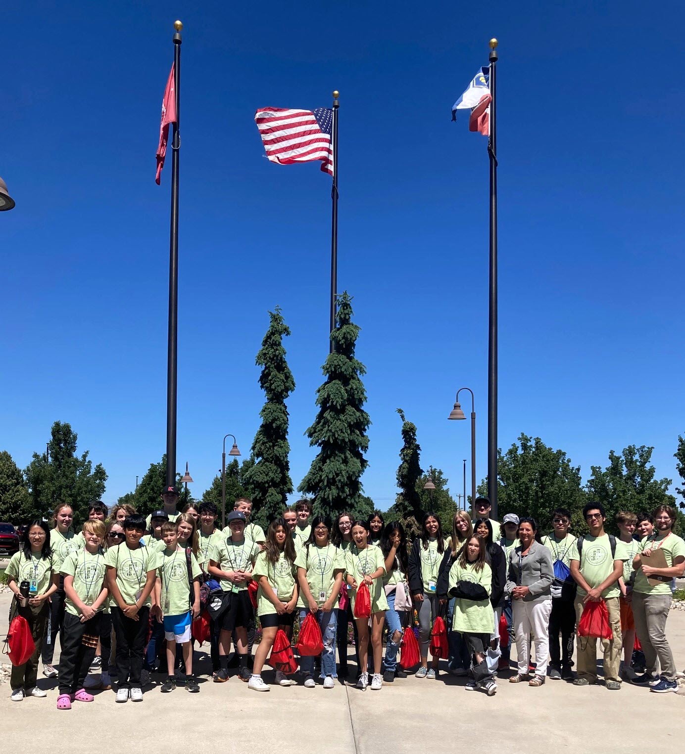 Image shows a number of high school-aged children in front of 3 flagpoles on the Merit Medical Salt Lake City campus