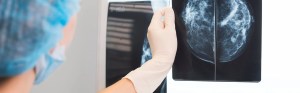 Capped physician looking at X-ray images of breast tissue