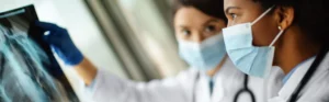 two masked female doctors looking at x-ray images