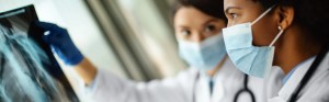two masked female doctors looking at x-ray images