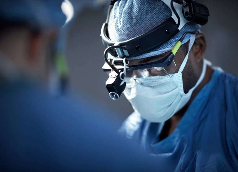 Black doctor, masked up, with a headlight and safety glasses on