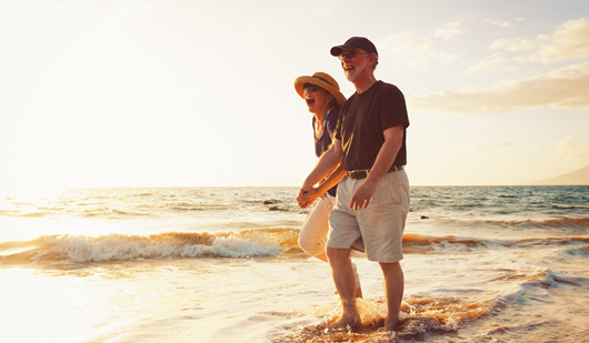 A couple in their sixties, playing and laughing together on the beach