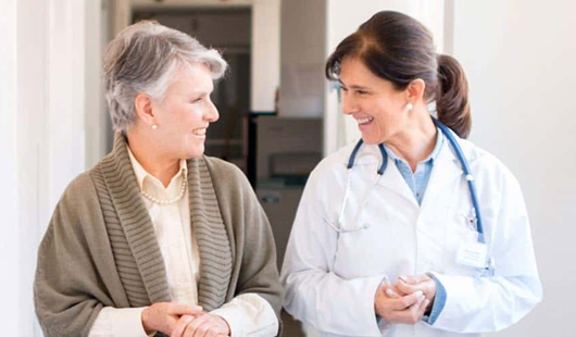 Two women - a patient and her female doctor - walking together down a hall
